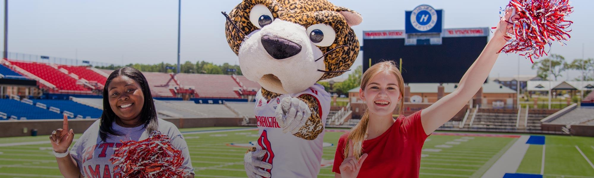 Two female students with 南 Paw in Hancock Whitney Stadium